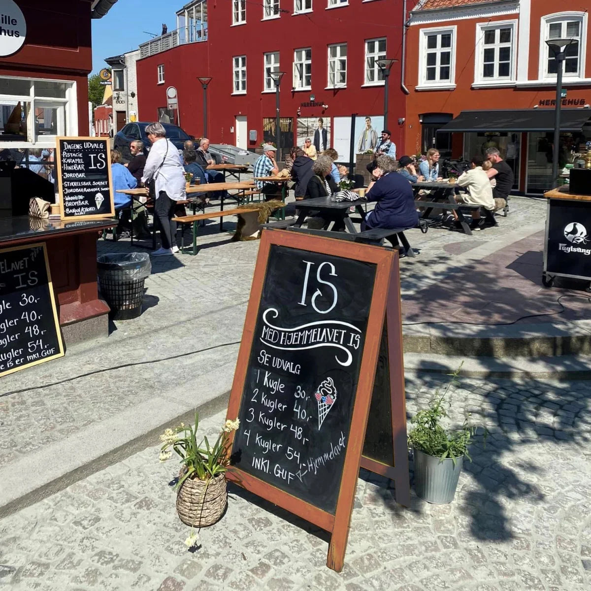Kundenstopper mit Kreidetafel vor einem Café mit Außenbestuhlung als Werbemittel für Laufkundschaft