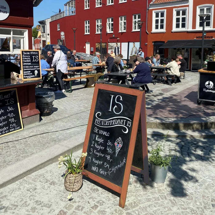 Kundenstopper mit Kreidetafel vor einem Café mit Außenbestuhlung als Werbemittel für Laufkundschaft