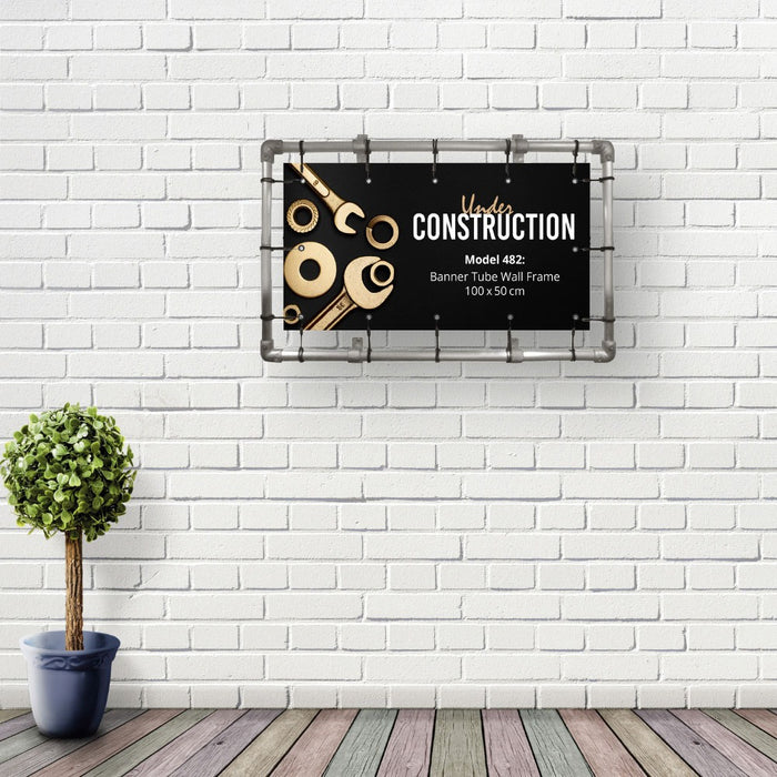 Bannerrahmen 100 x 50 cm mit Banner an einer weißen Ziegelwand montiert